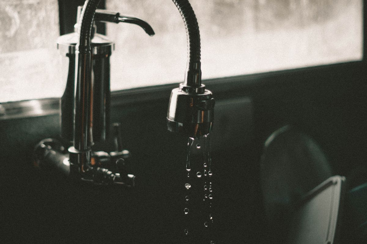 Water droplets falling from a kitchen faucet into a sink